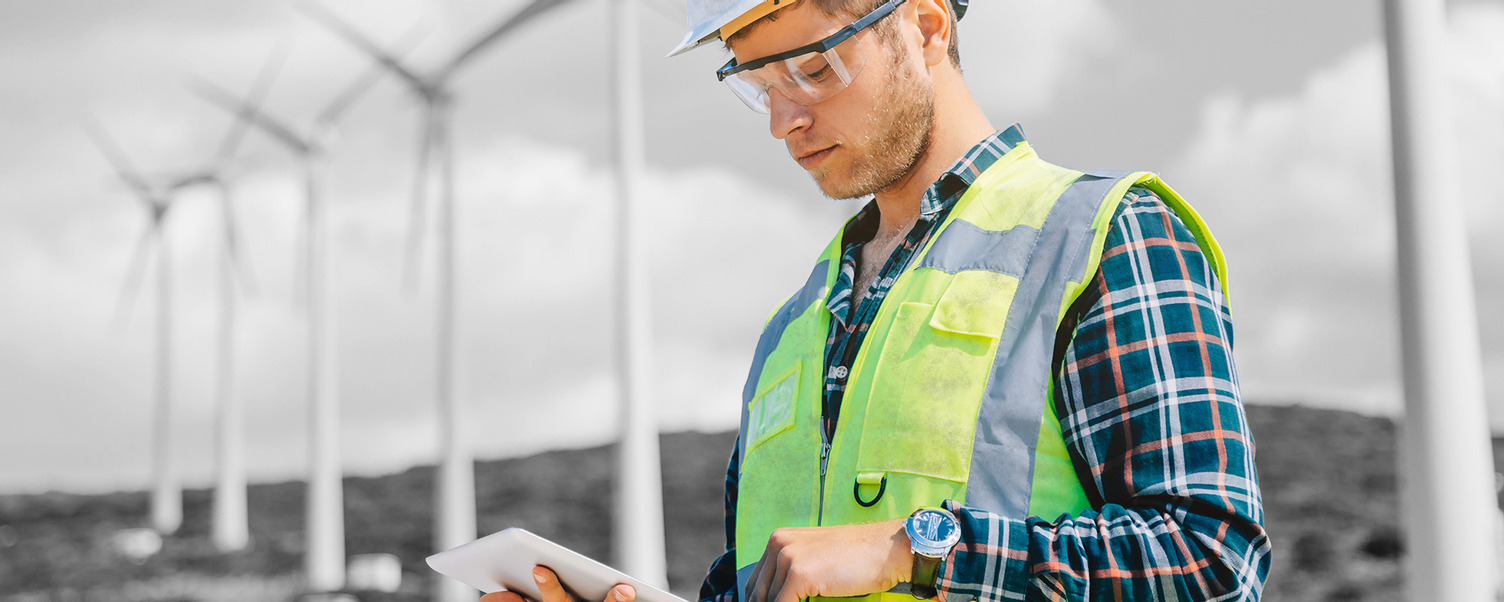 field engineer wearing high visual vest out at a windmill farm