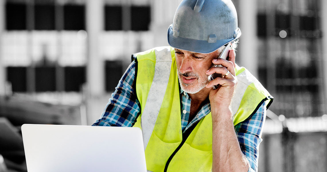 superintendent with high visual vest on the phone working